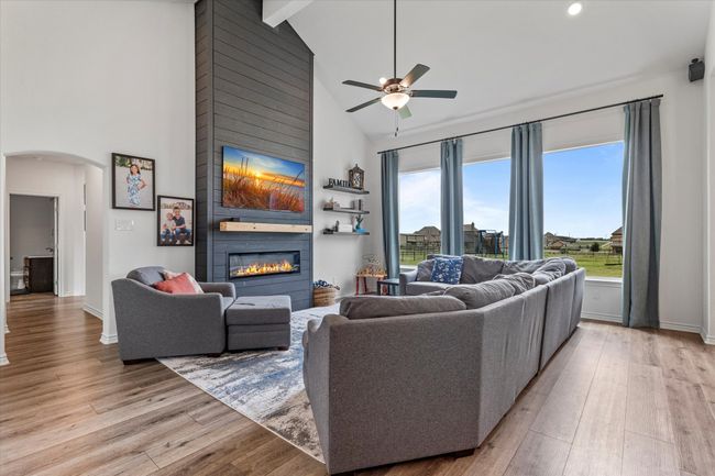 Living room with high vaulted ceiling, a ceiling fan, arched walkways, light wood-style flooring, and a fireplace | Image 8