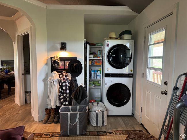 Washroom featuring stacked washer and clothes dryer, arched walkways, and wood finished floors | Image 10