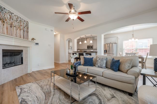 Living room with a ceiling fan, arched walkways, light wood-type flooring, ornamental molding, and a tile fireplace | Image 12