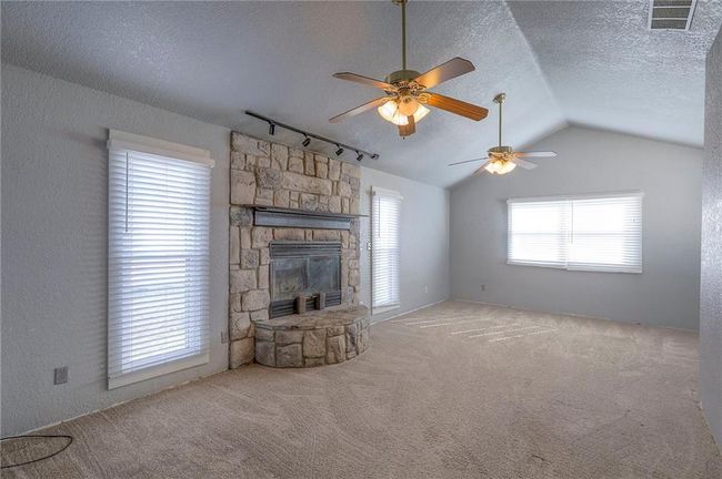 Unfurnished living room featuring vaulted ceiling, a textured ceiling, carpet floors, visible vents, and ceiling fan | Image 20