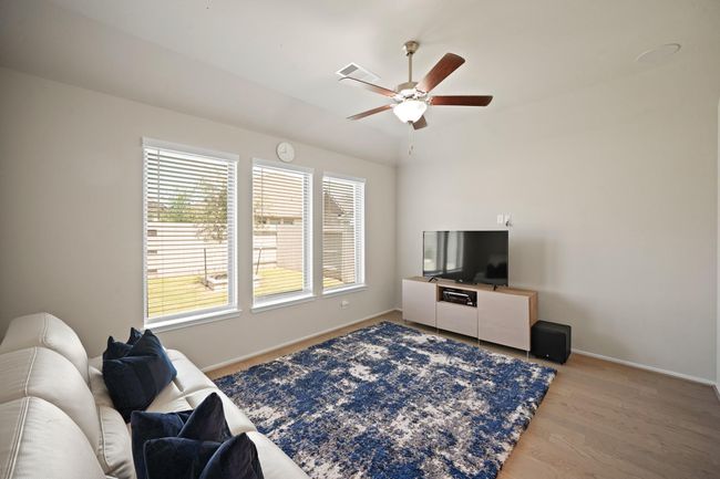 The game room features large windows, high ceiling, ceiling fan, and beautiful floors. | Image 23