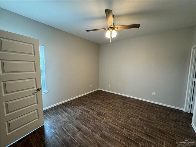 Empty room featuring ceiling fan, dark wood finished floors, and baseboards | Image 10