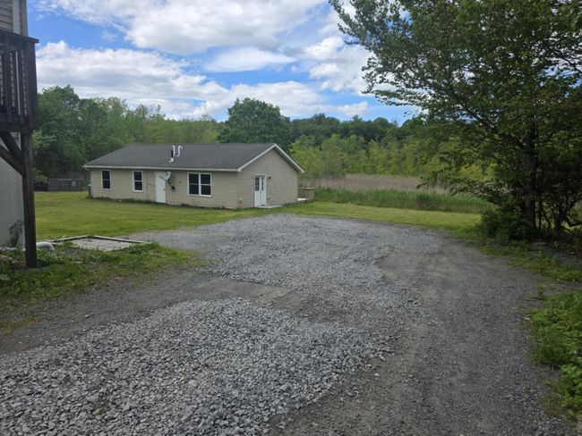 Single story home featuring driveway, a front lawn, and a forest view | Image 9
