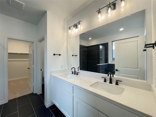 Full bathroom featuring double vanity, tile patterned floors, a walk in closet, and a tile shower | Image 13