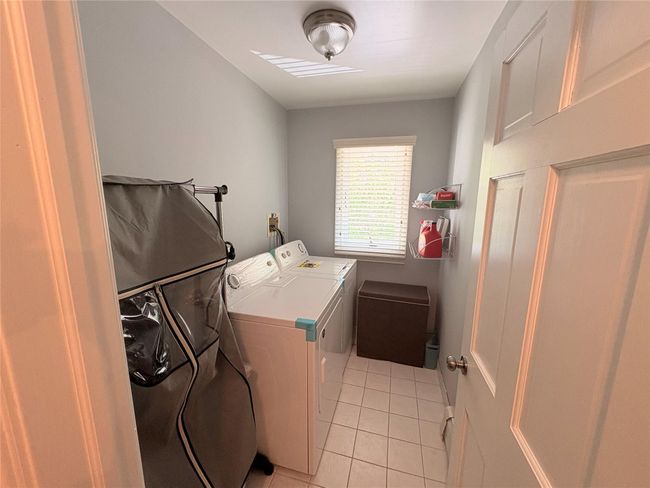 Laundry area with light tile patterned floors and washing machine and clothes dryer | Image 13