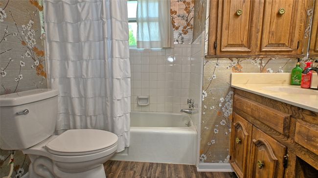 Bathroom featuring wood finished floors, toilet, vanity, and shower / bathtub combination with curtain | Image 7