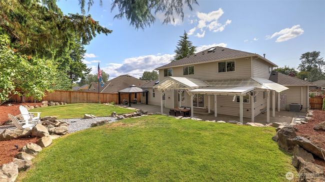 Full view of the wide-open green lawn and rock-covered cement area, highlighting the large covered spaces, perfect for serene and peaceful relaxation. Surrounding dirt areas provide excellent opportunities for gardening and planting | Image 34