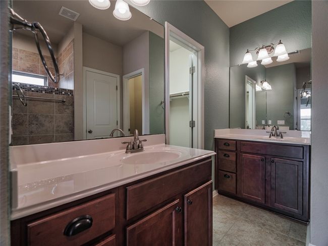 Full bathroom with vanity, tile patterned floors, a shower, and a textured wall | Image 28