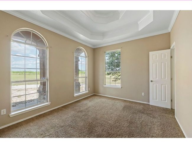 Carpeted empty room featuring a tray ceiling and ornamental molding | Image 7