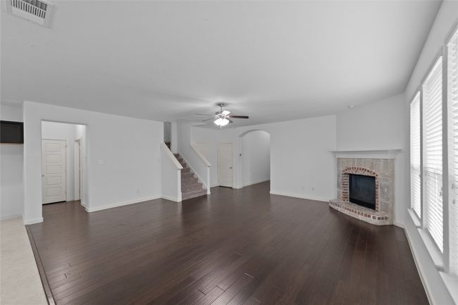 Unfurnished living room featuring a fireplace, stairs, and dark wood finished floors | Image 7
