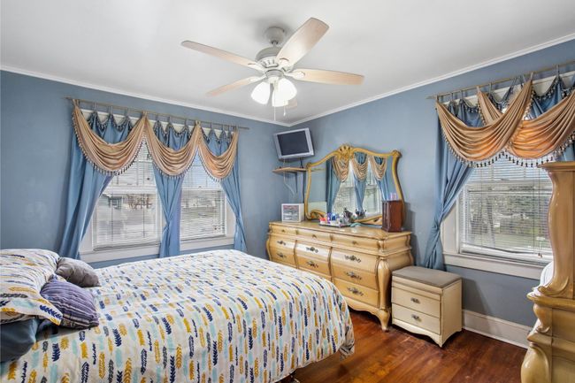 Bedroom with ceiling fan, baseboards, ornamental molding, and wood finished floors | Image 16