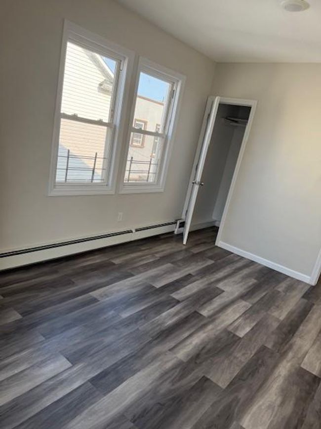 Unfurnished bedroom with baseboard heating and dark wood-type flooring | Image 11