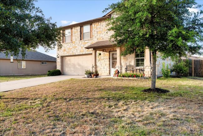 Traditional home featuring stone siding, an attached garage, and driveway | Image 36