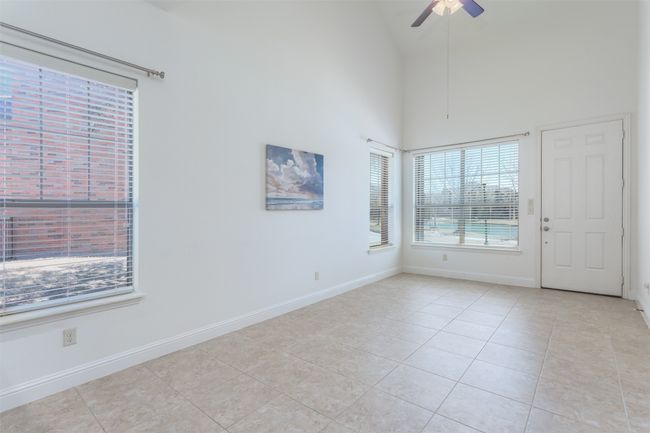 Unfurnished room featuring light tile patterned flooring, a ceiling fan, baseboards, and high vaulted ceiling | Image 7