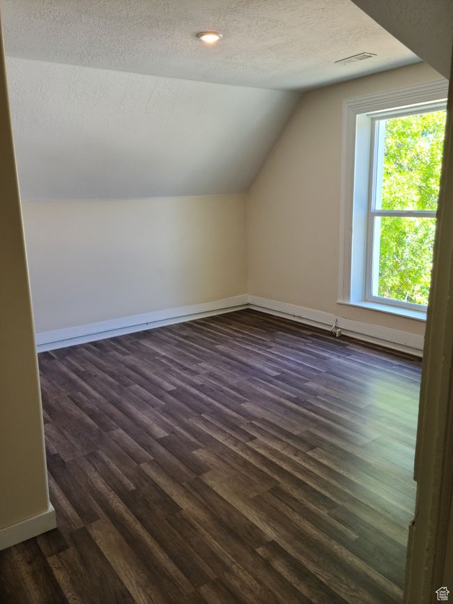 Additional living space featuring vaulted ceiling, a textured ceiling, dark wood-type flooring, and baseboards | Image 26