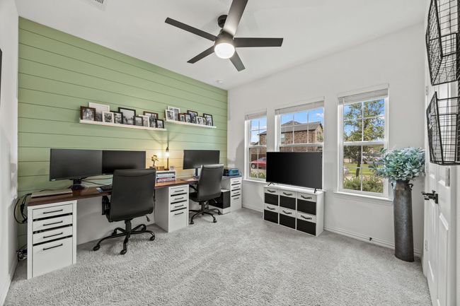 Carpeted office space featuring ceiling fan and wood walls | Image 11