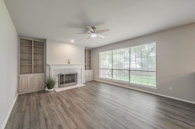 Family room with wood burning fireplace ready for cozy evenings is flanked by shelves & cabinets for books, games, etc. | Image 18