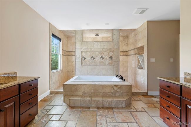 Full bath featuring vanity, stone tile flooring, a relaxing tiled tub, and a walk in shower | Image 31