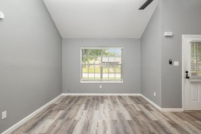 Unfurnished room with lofted ceiling, wood finished floors, baseboards, a textured wall, and a ceiling fan | Image 9