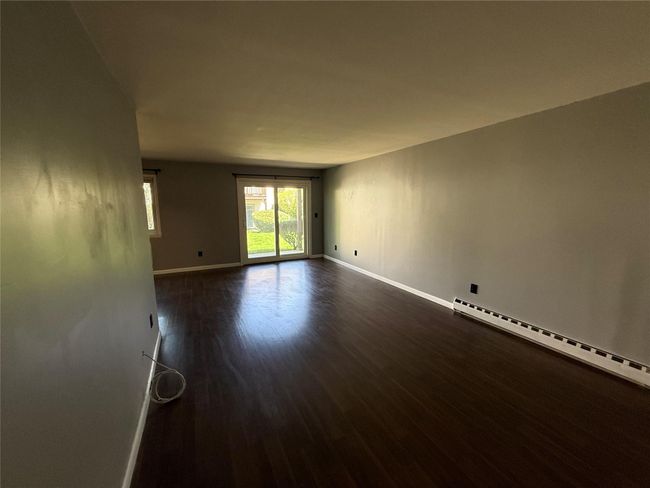 Empty room featuring a baseboard radiator, dark wood-style flooring, and baseboards | Image 10