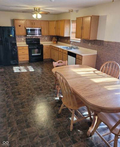 large kitchen with lots of cabinets/counter top, and 80" long table | Image 3