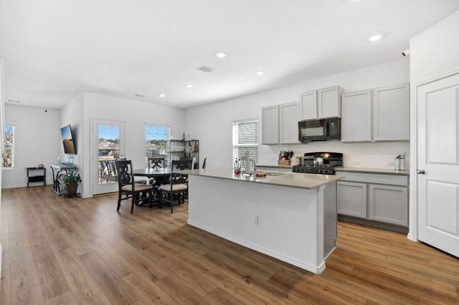 Kitchen featuring range, a kitchen island with sink, light countertops, gray cabinetry, and black microwave | Image 10