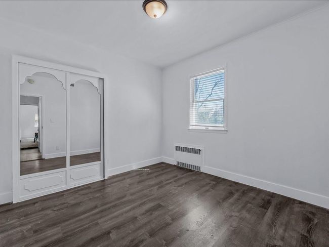 Unfurnished bedroom featuring radiator heating unit, dark wood finished floors, baseboards, and a closet | Image 13