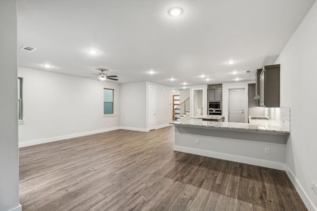 Kitchen featuring recessed lighting, wood finished floors, ceiling fan, light stone countertops, and a peninsula | Image 15