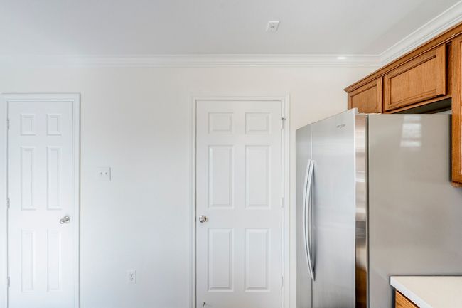 Kitchen featuring freestanding refrigerator, ornamental molding, brown cabinetry, and light countertops | Image 10