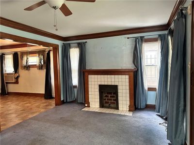 Unfurnished living room featuring a tile fireplace, crown molding, light carpet, and ceiling fan | Image 3