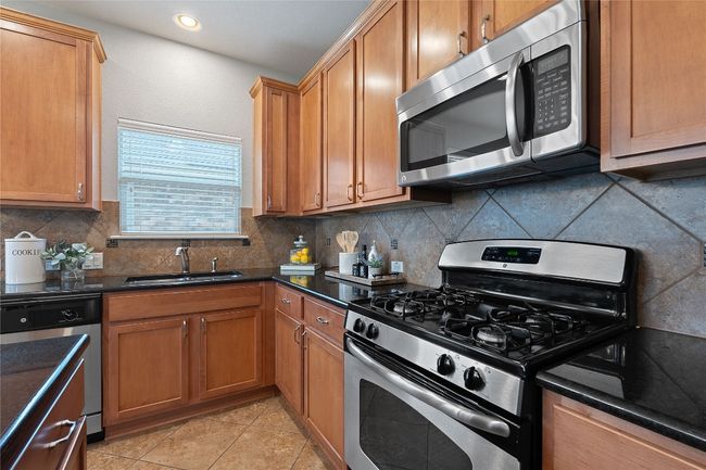 Kitchen featuring stainless steel appliances, tasteful backsplash, light tile patterned floors, recessed lighting, and brown cabinetry | Image 18