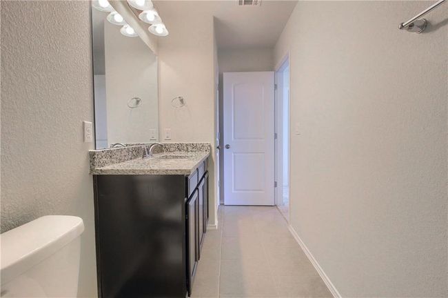 Bathroom featuring vanity, tile patterned floors, toilet, and a textured wall | Image 34