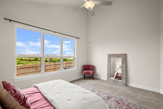 Bedroom featuring carpet floors, multiple windows, a high ceiling, and a ceiling fan | Image 11
