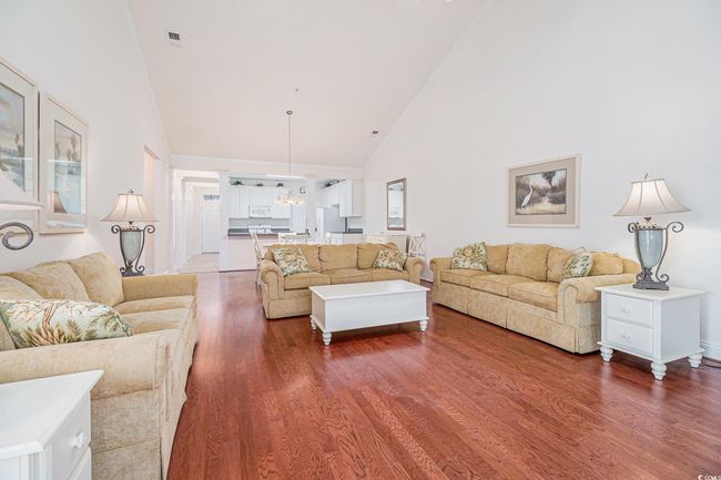 Living area with high vaulted ceiling, wood finished floors, and a chandelier | Image 6