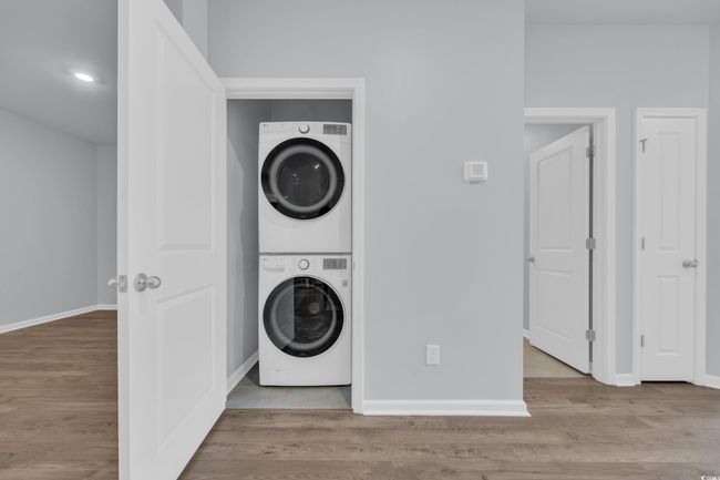 Laundry area with baseboards, stacked washer and dryer, wood finished floors, and laundry area | Image 14