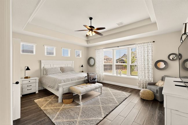 Bedroom with a tray ceiling, dark wood-style floors, baseboards, and ceiling fan | Image 12