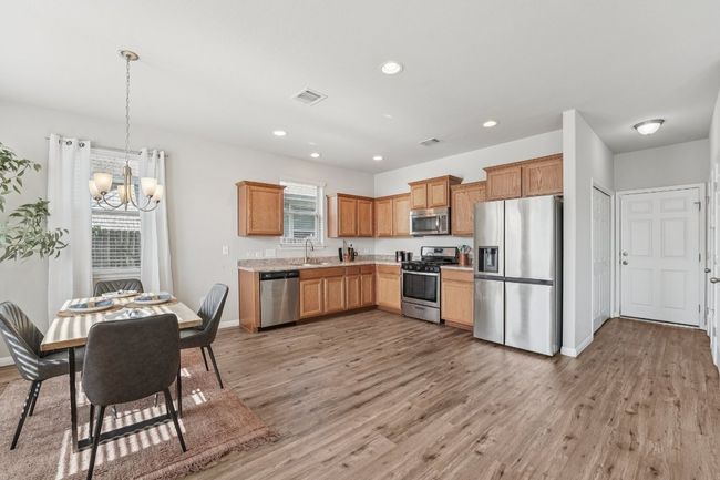 Kitchen with stainless steel appliances, a chandelier, light countertops, light wood finished floors, and recessed lighting | Image 10