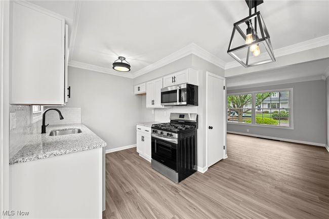 Kitchen with light stone counters, stainless steel appliances, light wood-style floors, a sink, and baseboards | Image 14