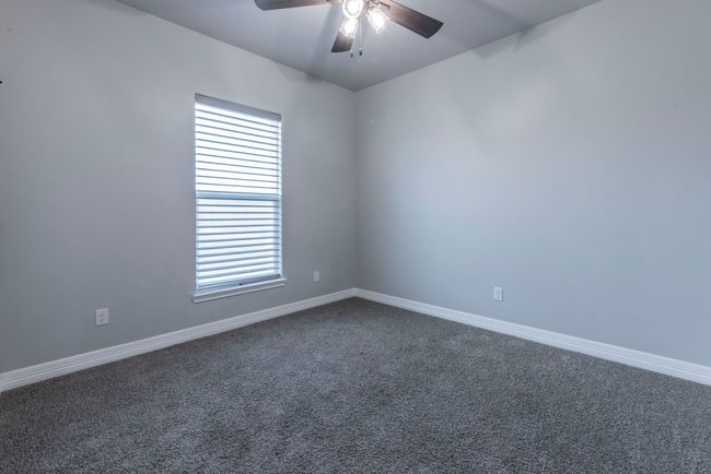Empty room featuring a ceiling fan, dark colored carpet, and plenty of natural light | Image 20