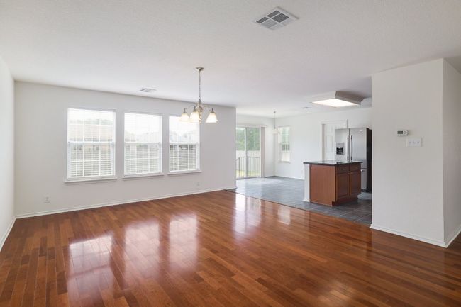 Unfurnished living room featuring dark wood-style floors, visible vents, an inviting chandelier, and baseboards | Image 9
