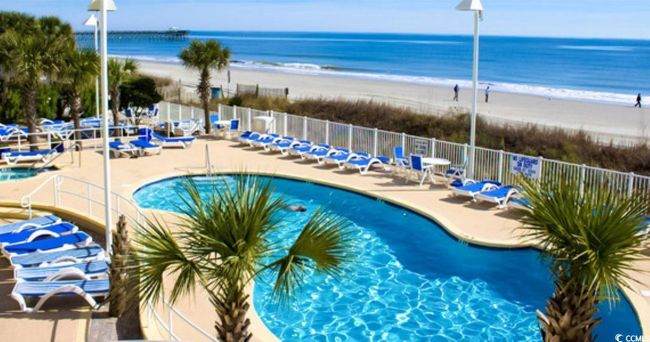 Community pool featuring view of water and beach and a patio area | Image 23