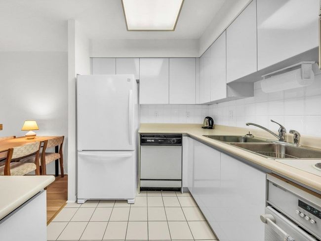 Kitchen with white appliances, white cabinets, a sink, and backsplash | Image 7