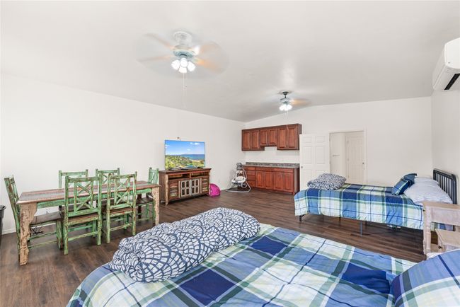 Bedroom featuring an AC wall unit, lofted ceiling, dark wood finished floors, and a ceiling fan | Image 34