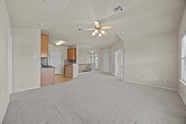 Unfurnished living room featuring a ceiling fan, visible vents, light carpet, and baseboards | Image 11