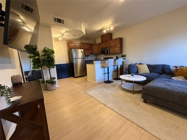 Living room with light wood-type flooring, visible vents, and track lighting | Image 4