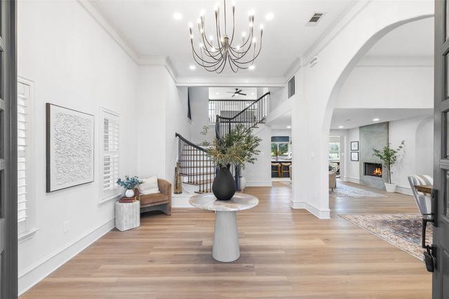 Foyer with stairs, arched walkways, a fireplace, crown molding, and light wood-style floors | Image 4