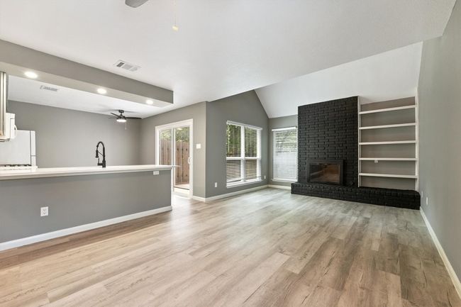 Unfurnished living room with a ceiling fan, light wood-style flooring, baseboards, a fireplace, and recessed lighting | Image 9