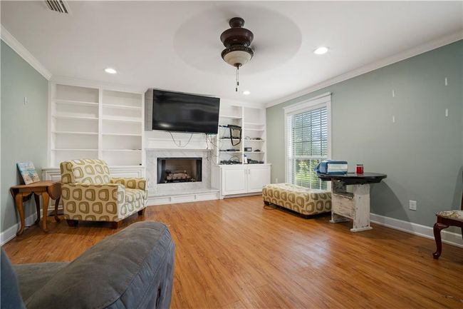 Living area with visible vents, wood finished floors, ornamental molding, and a ceiling fan | Image 15