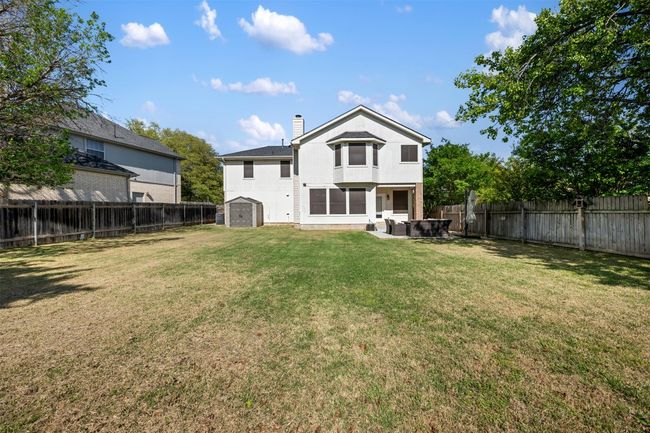 Back of house with an outdoor structure, a chimney, a fenced backyard, a storage shed, and a lawn | Image 37