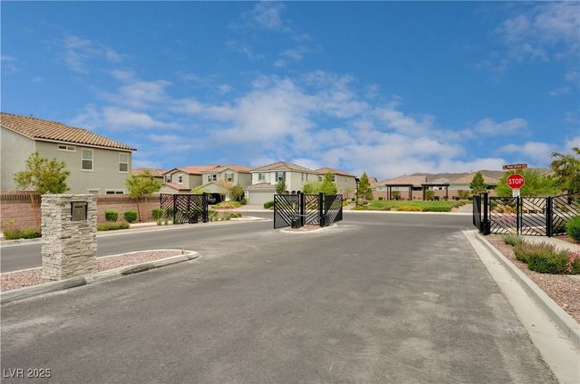 View of asphalt street with a residential view, traffic signs, curbs, and a gated entry | Image 37